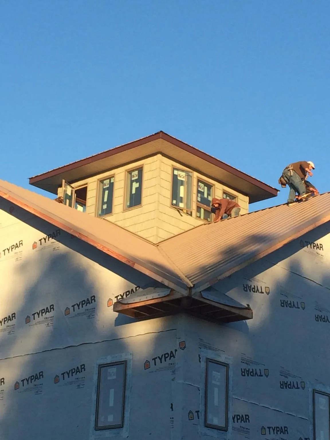 Roofers working around a rooftop cupola on a new metal roof at sunset — Roof Waterproofing in Carthage by Roofing Brothers